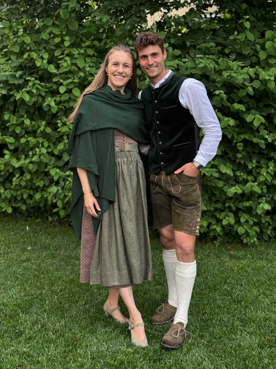 Frau und Mann in Tracht vor einer grünen Hecke