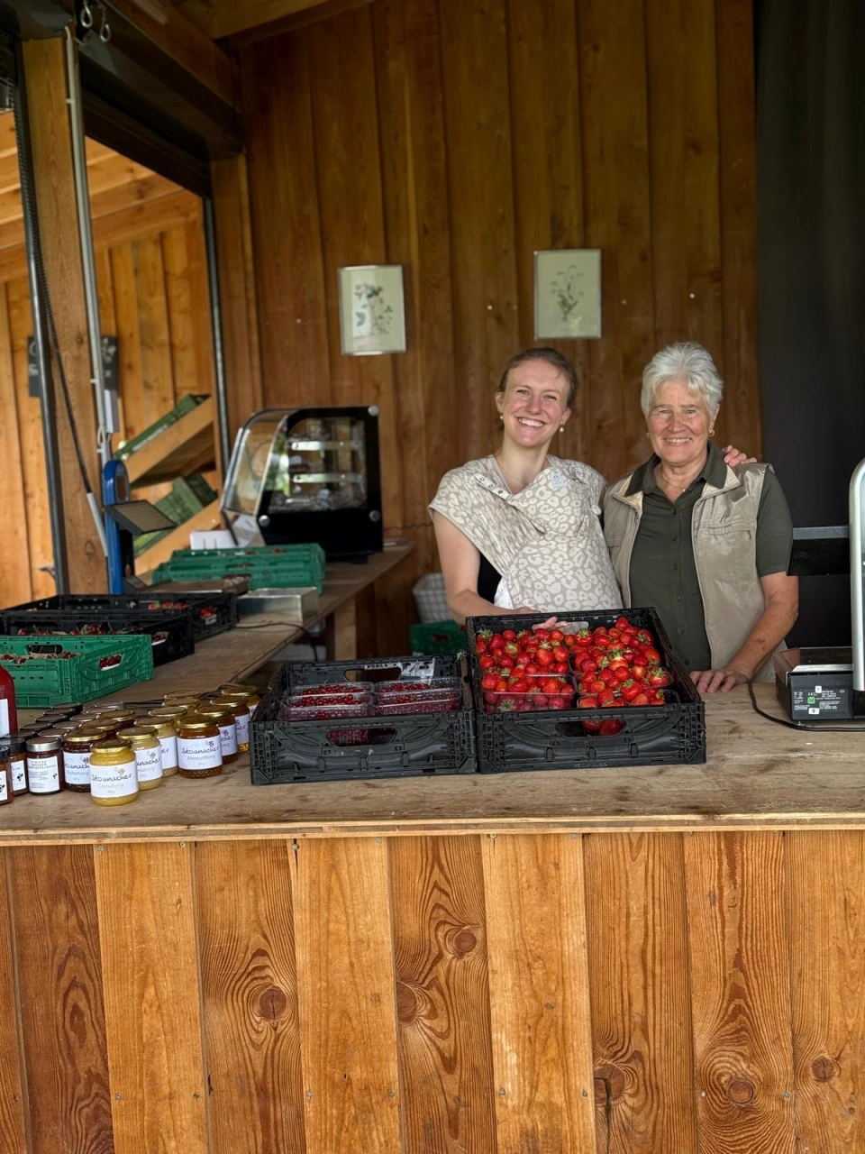 Junge und ältere Frau am Verkaufsstand mit Erdbeeren und roten Ribiseln