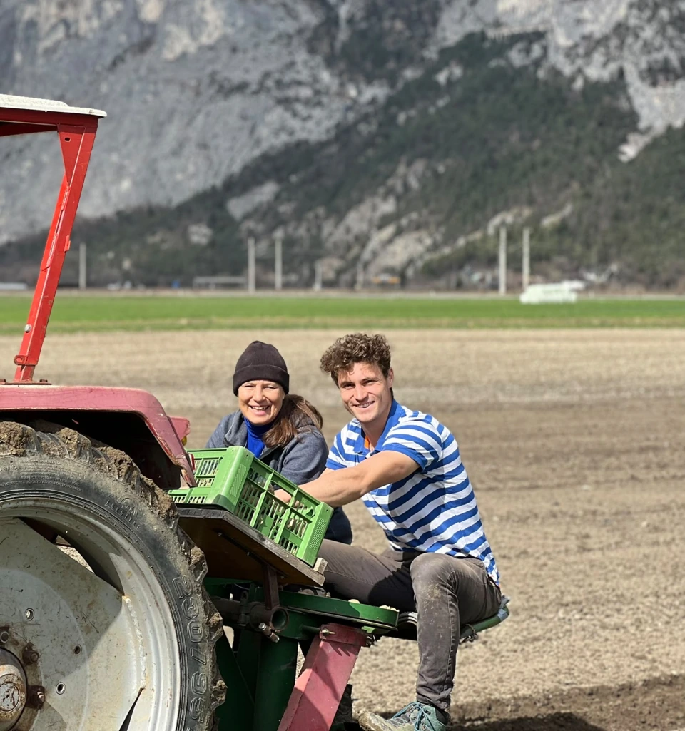 Zwei Menschen mit grünen Kisten am Traktor